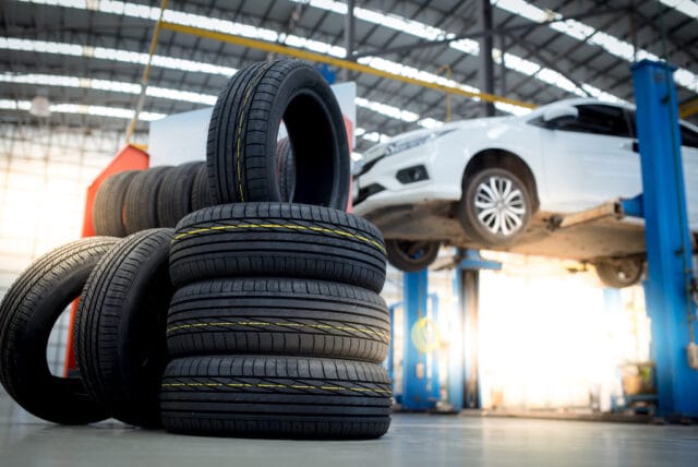 new tires that change tires in the auto repair service center, blurred background, the background is a new car in the stock blur for the industry, a four-wheeled tire set at a large warehouse
